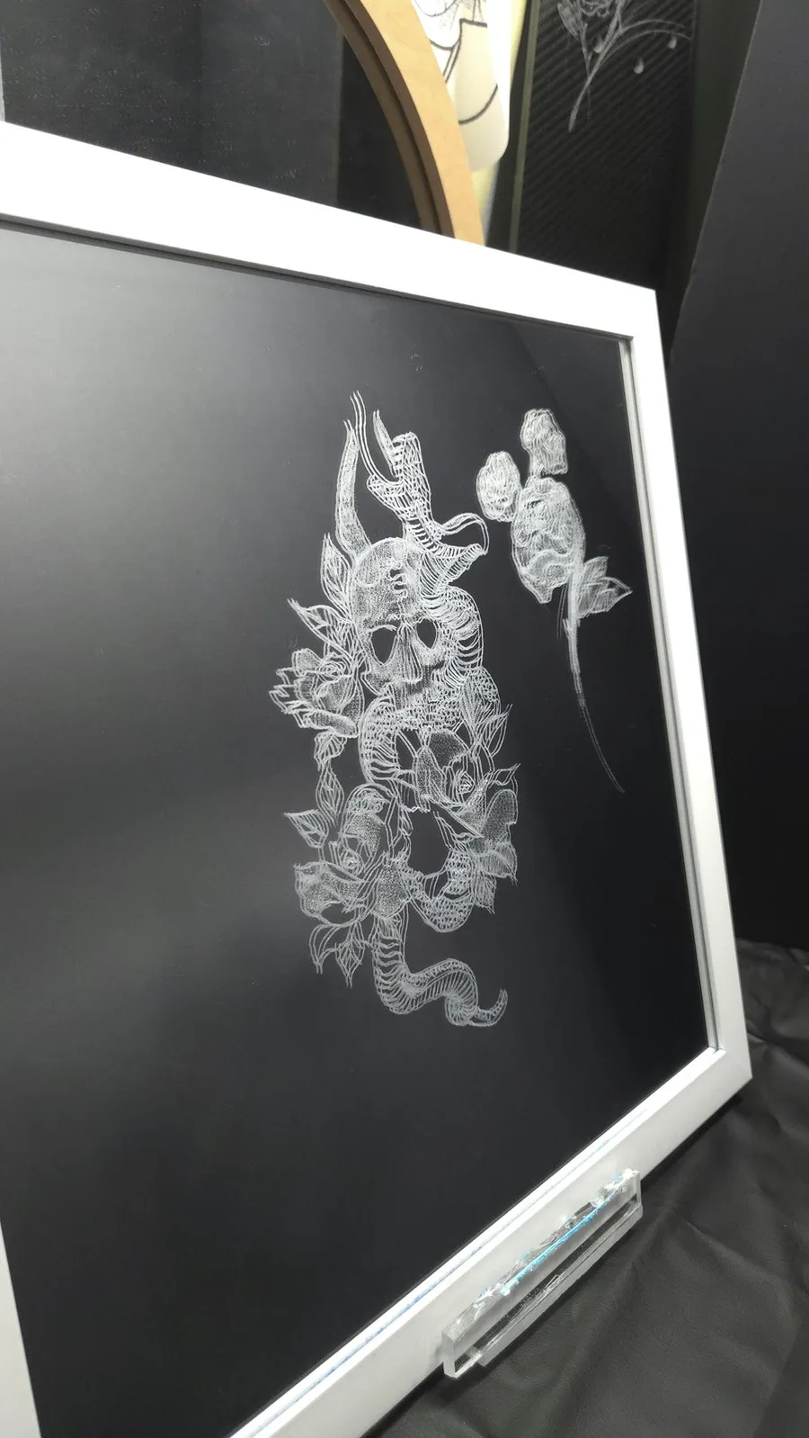 Skull entwined with a snake amid roses, hand-etched on a mirror